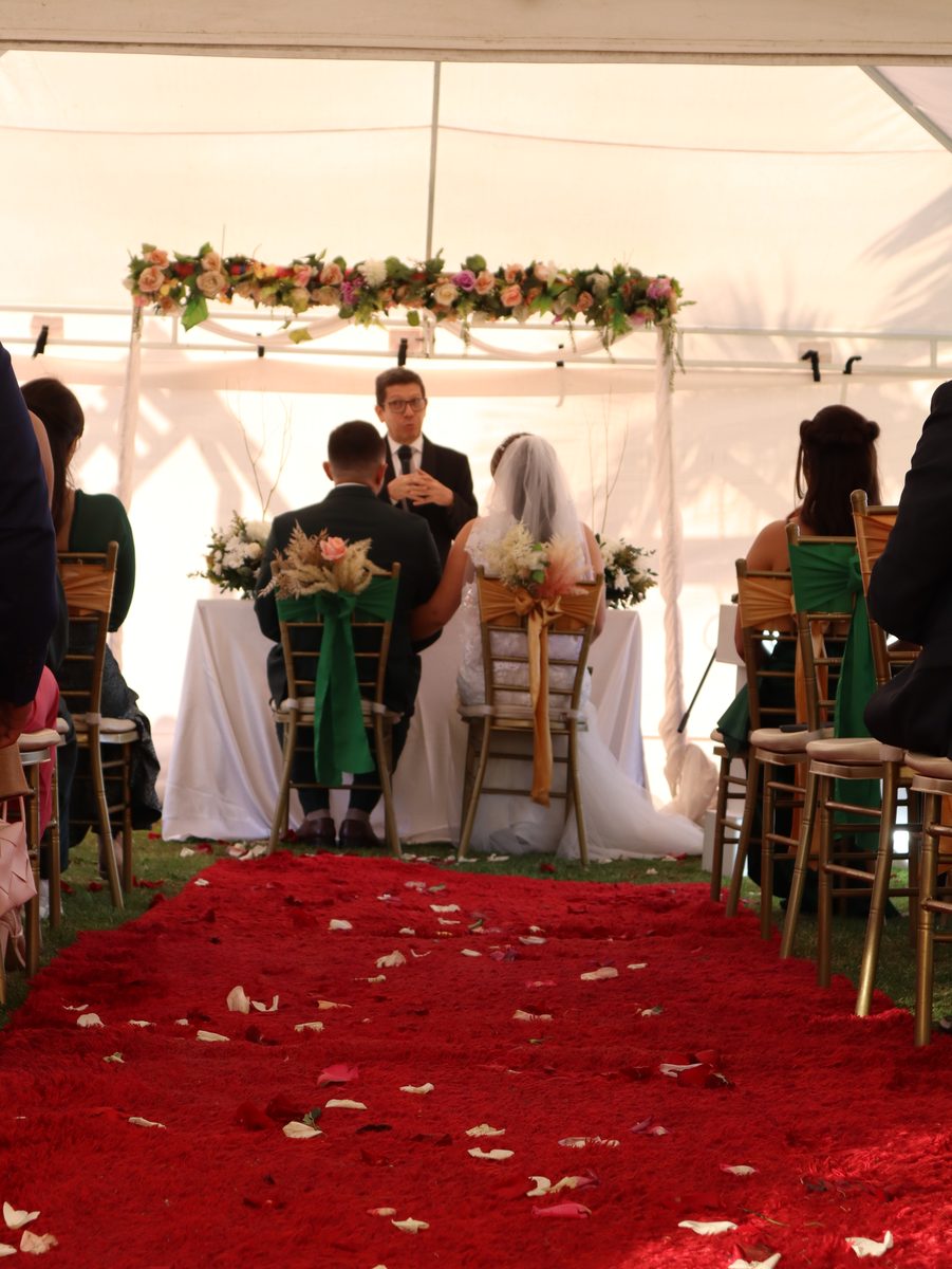 Pasillo de ceremonia con alfombra y arco floral al aire libre