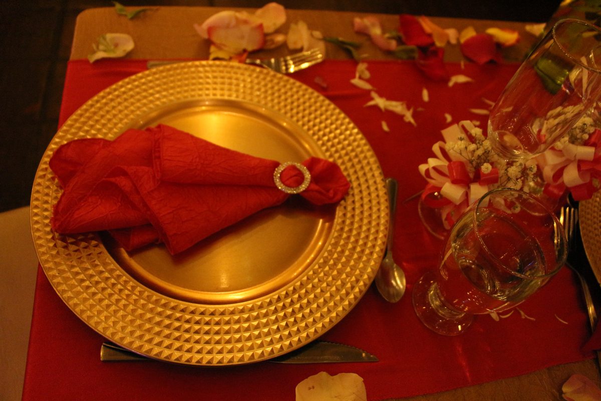 Plato dorado sobre mantel rojo con pétalos