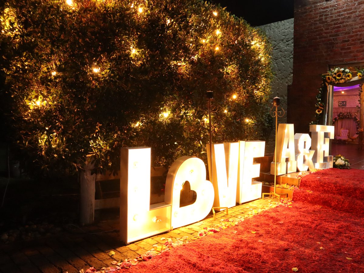 Letras iluminadas con las iniciales de los novios en el jardín