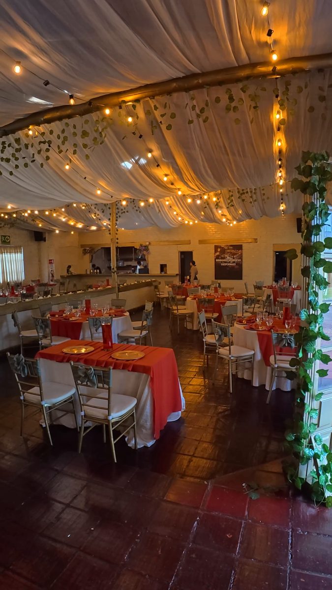 Salón montado con mesas en rojo y luces colgantes