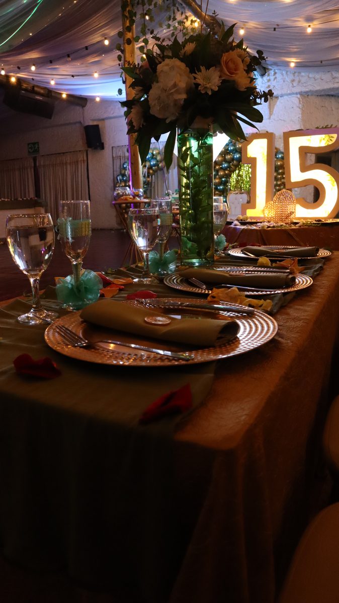 Puesto de mesa con centro floral y las letras iluminadas al fondo