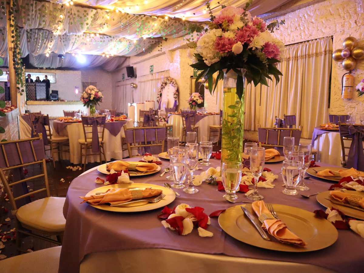 Mesas montadas en lila y dorado con centros florales
