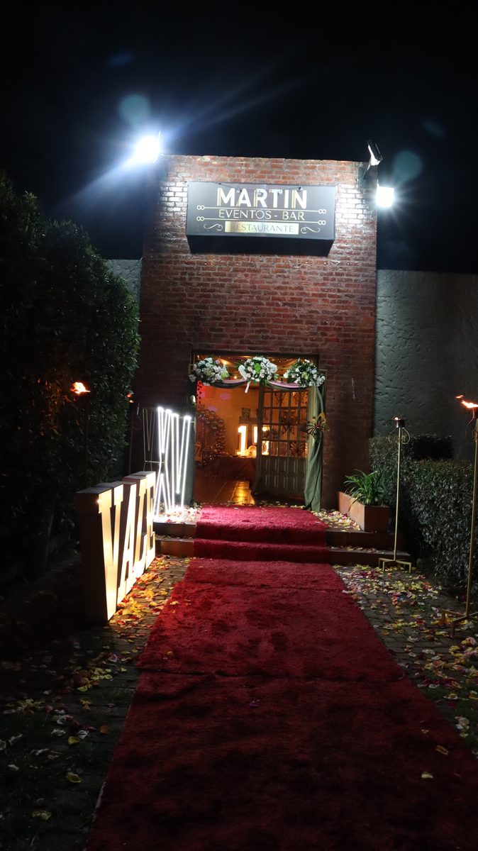Entrada del salón con alfombra roja y letras iluminadas