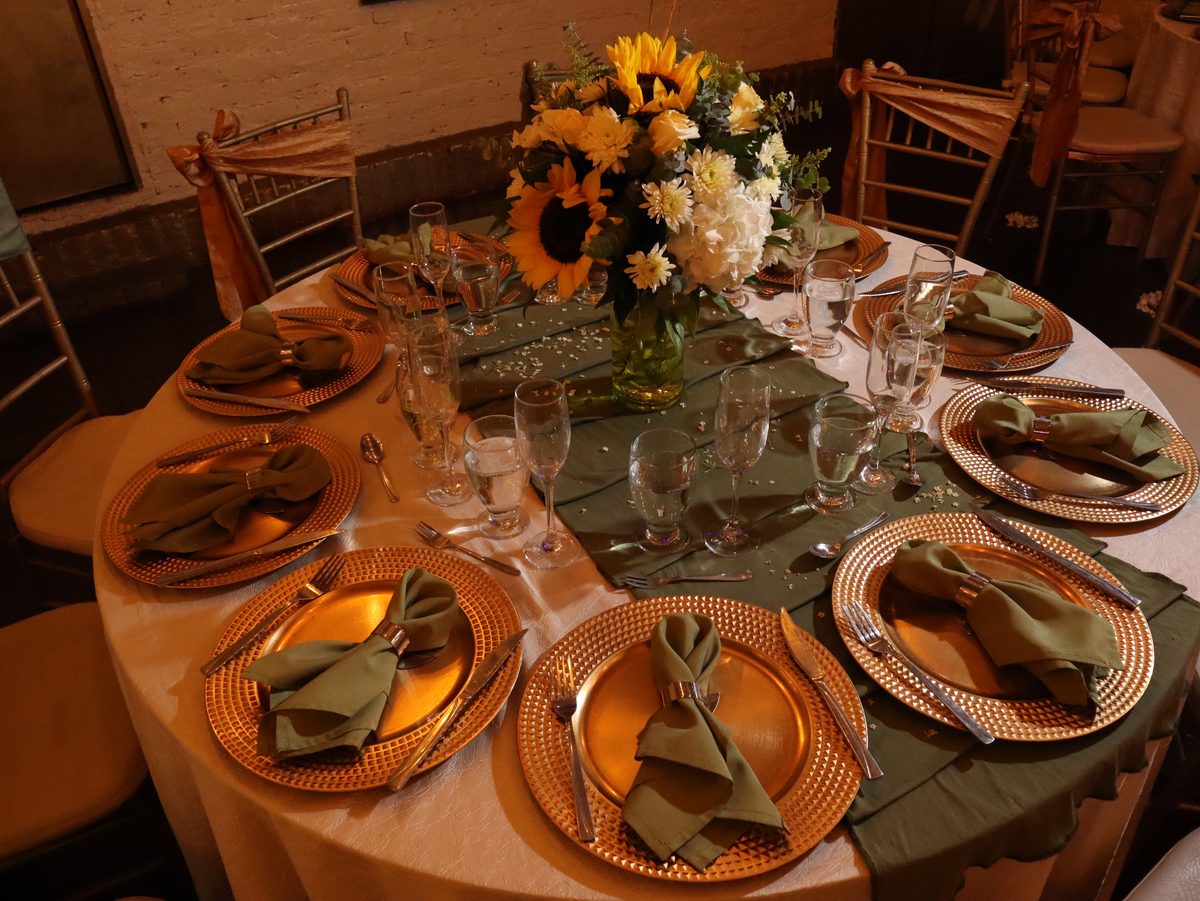 Mesa de boda montada en verde oliva y dorado con girasoles